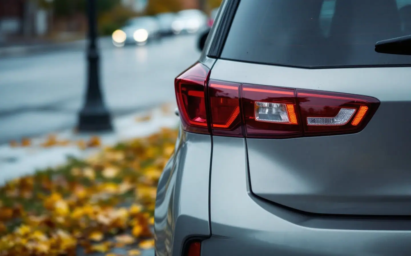 The rear of a parked sedan with an empty plate bracket on a quiet residential street at dusk